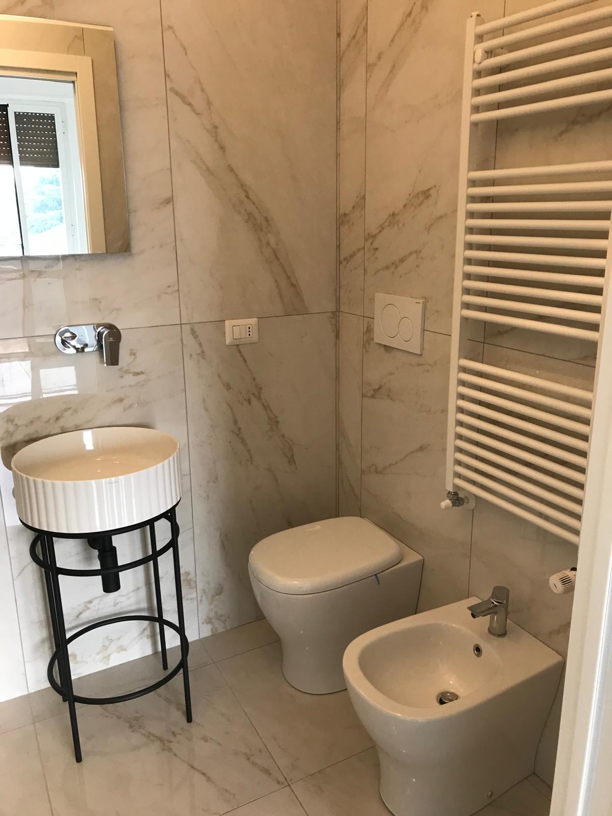 Bagno chiaro con lavabo design su struttura e gres effetto marmo